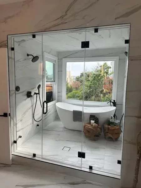 Bathroom with a freestanding tub, large mirror, and view of greenery outside.