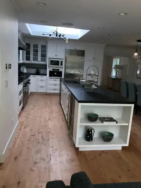 Modern kitchen with white cabinets, island, skylight, and hardwood floors
