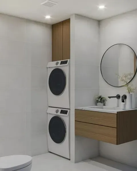 Modern bathroom with stacked washer-dryer, floating wood vanity, round mirror, and white tiled walls