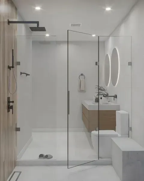 Modern white bathroom with walk-in shower, glass partition, wall mirror, and floating vanity.