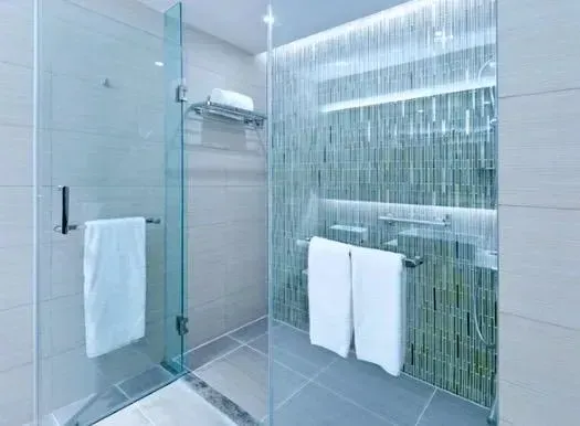 Modern bathroom shower with glass enclosure, tiled walls, and white towels on a railing