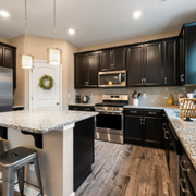 Modern kitchen with dark cabinets, granite countertops, stainless appliances, and a center island under pendant lights