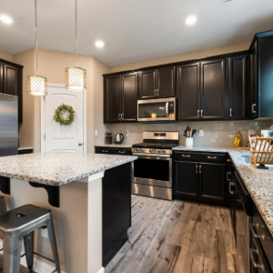 Modern kitchen with dark cabinets, granite countertops, stainless appliances, and a center island under pendant lights