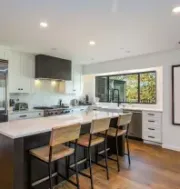 Modern dining room with set table, blue chairs, indoor plants, and large windows overlooking a pool