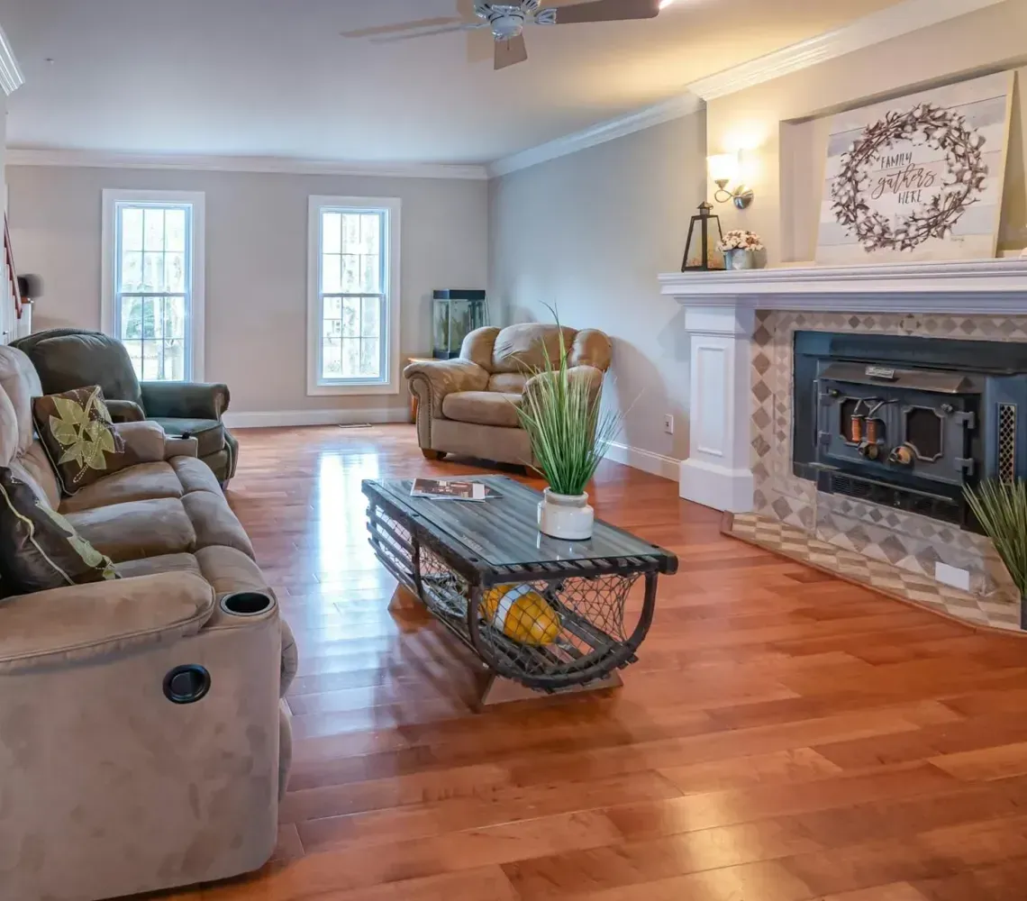 Bright living room with sofas, coffee table, fireplace, and warm wood floors