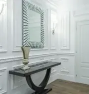 Elegant white hallway with paneled walls, decorative mirror, black console table, and wooden floor.