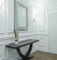 Elegant white hallway with paneled walls, decorative mirror, black console table, and wooden floor.