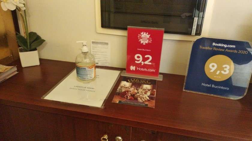 Un bancone di legno di un hotel con una bottiglia di disinfettante per le mani, un cartello con la valutazione.