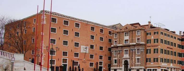 Two historic salmon-colored buildings in Venice, Italy, featuring multiple windows and architectural details.