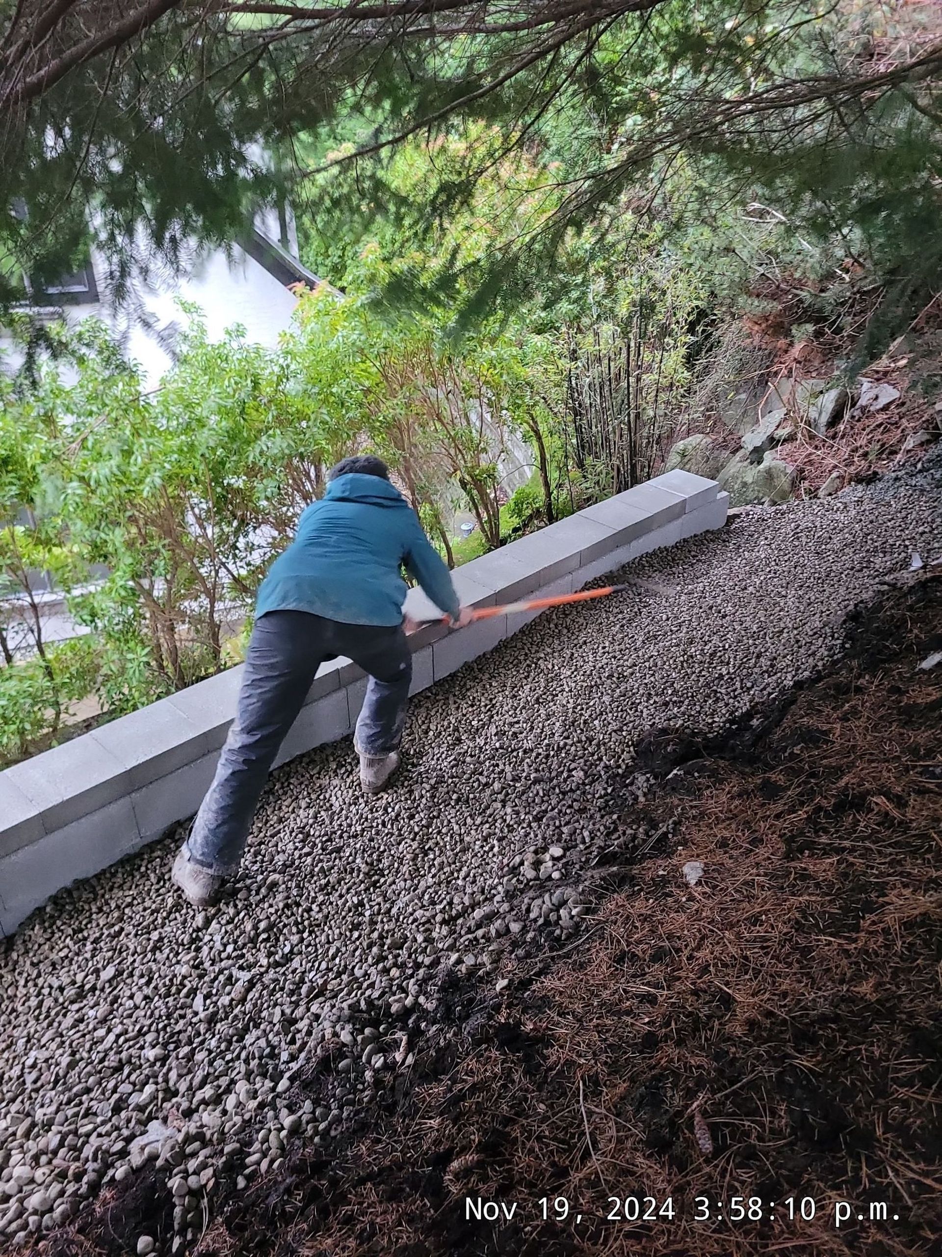 A person is climbing up a rocky hill with a broom.