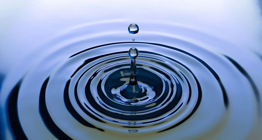 A water droplet falling into a pool, creating concentric ripples.