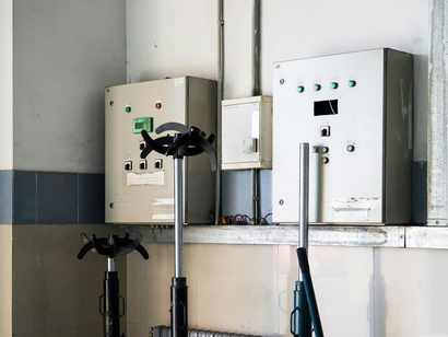 Electrical panels mounted on a wall with support poles in an industrial setting.
