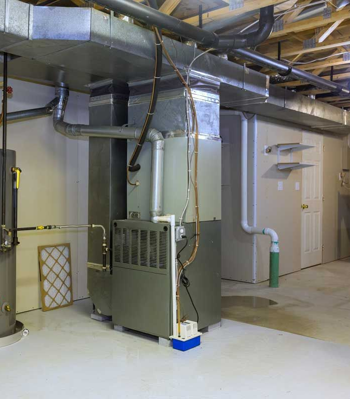 Basement with furnace, ductwork, water heater, and a door. Gray and white tones dominate.