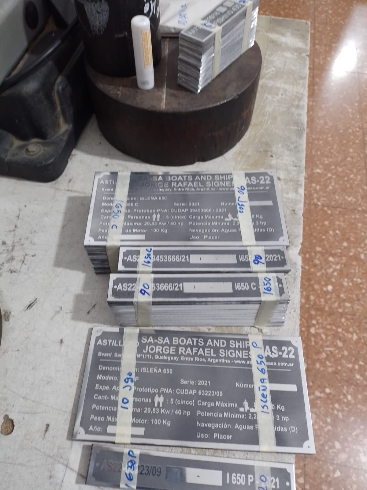 Una pila de placas conmemorativas grabadas en el suelo, junto a una mesa redonda y pequeños objetos.