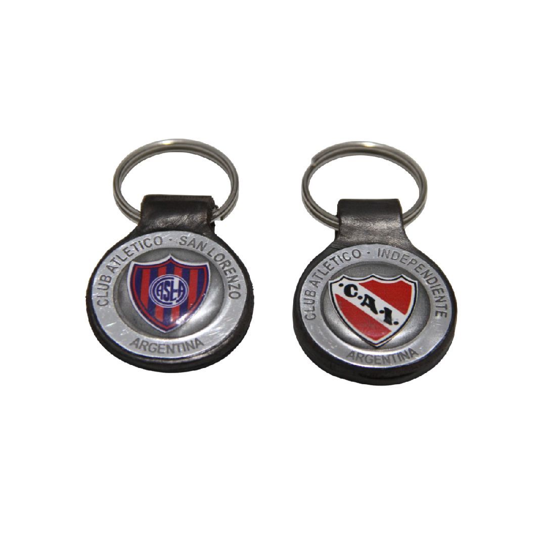 Dos llaveros plateados con emblemas circulares de equipos deportivos, uno azul y rojo y otro rojo, blanco y negro.