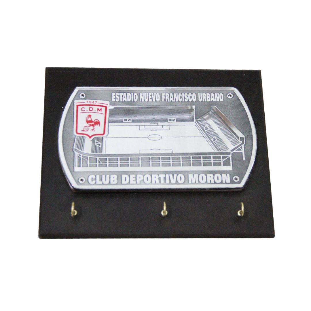 Placa de pared negra con una placa plateada del club Atlético Patronato y tres ganchos dorados debajo.