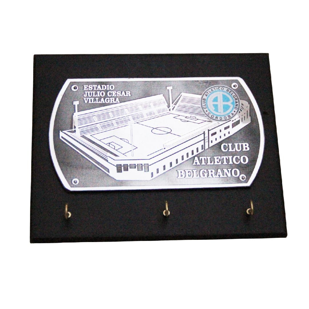 Placa negra con un grabado plateado de un estadio con la inscripción “Club Atlético Belgrano” y tres ganchos debajo.