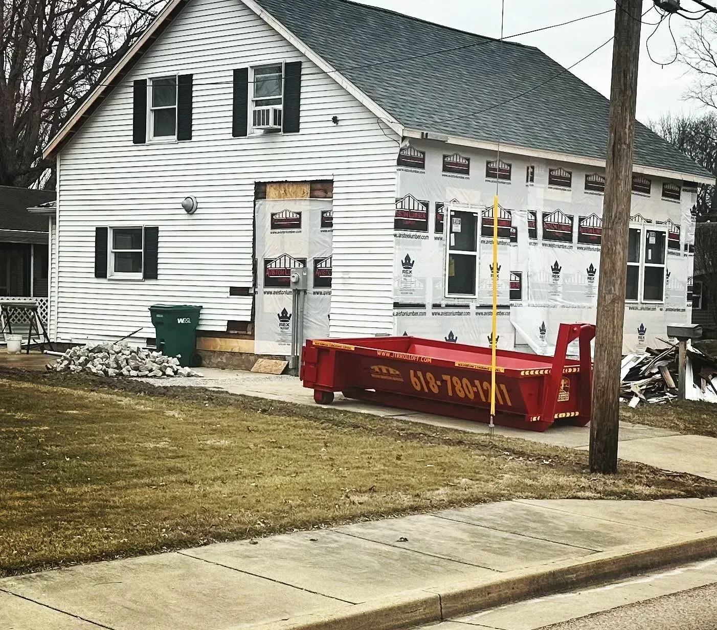 A white house with a red dumpster in front of it