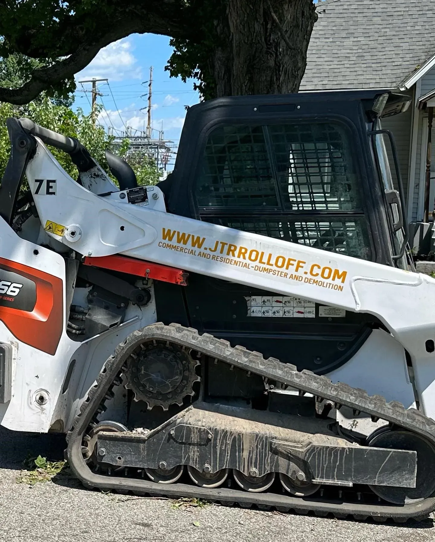 A bobcat track loader is parked in front of a house.
