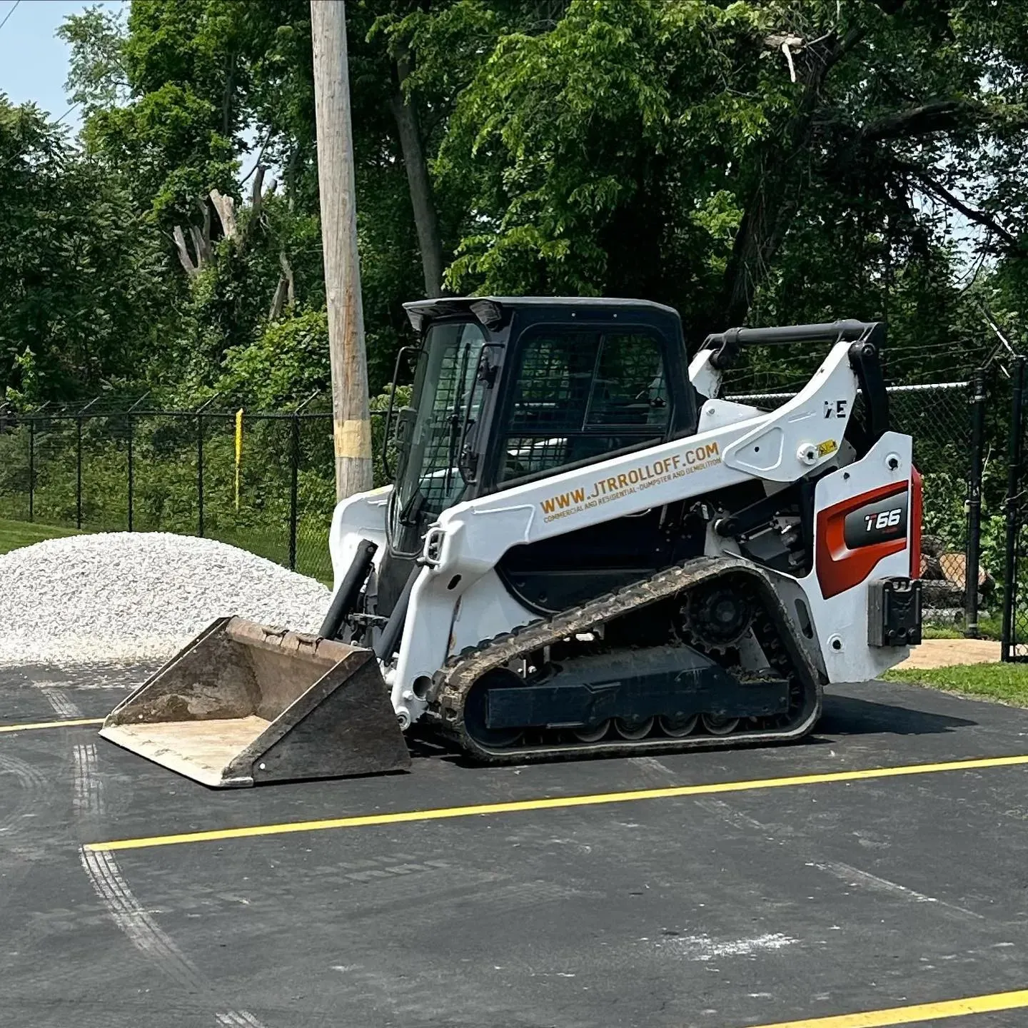 A bulldozer is parked in a parking lot next to a pile of gravel.
