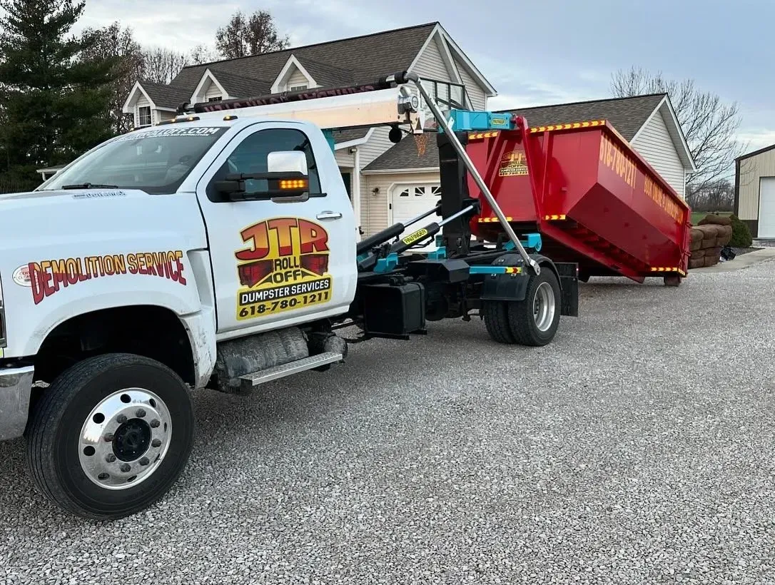 A dumpster truck is parked in front of a house.