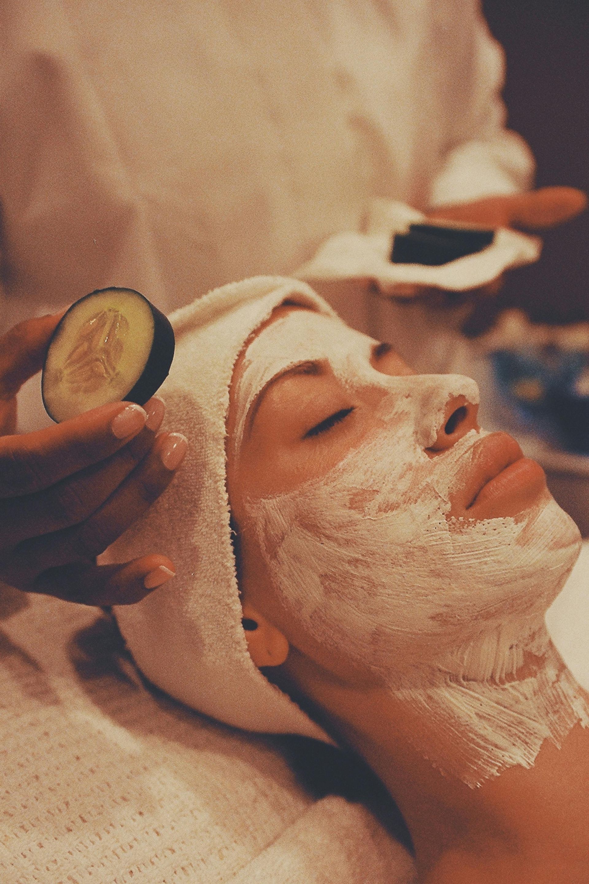 Person receiving a facial mask treatment with a towel wrapped around the head.