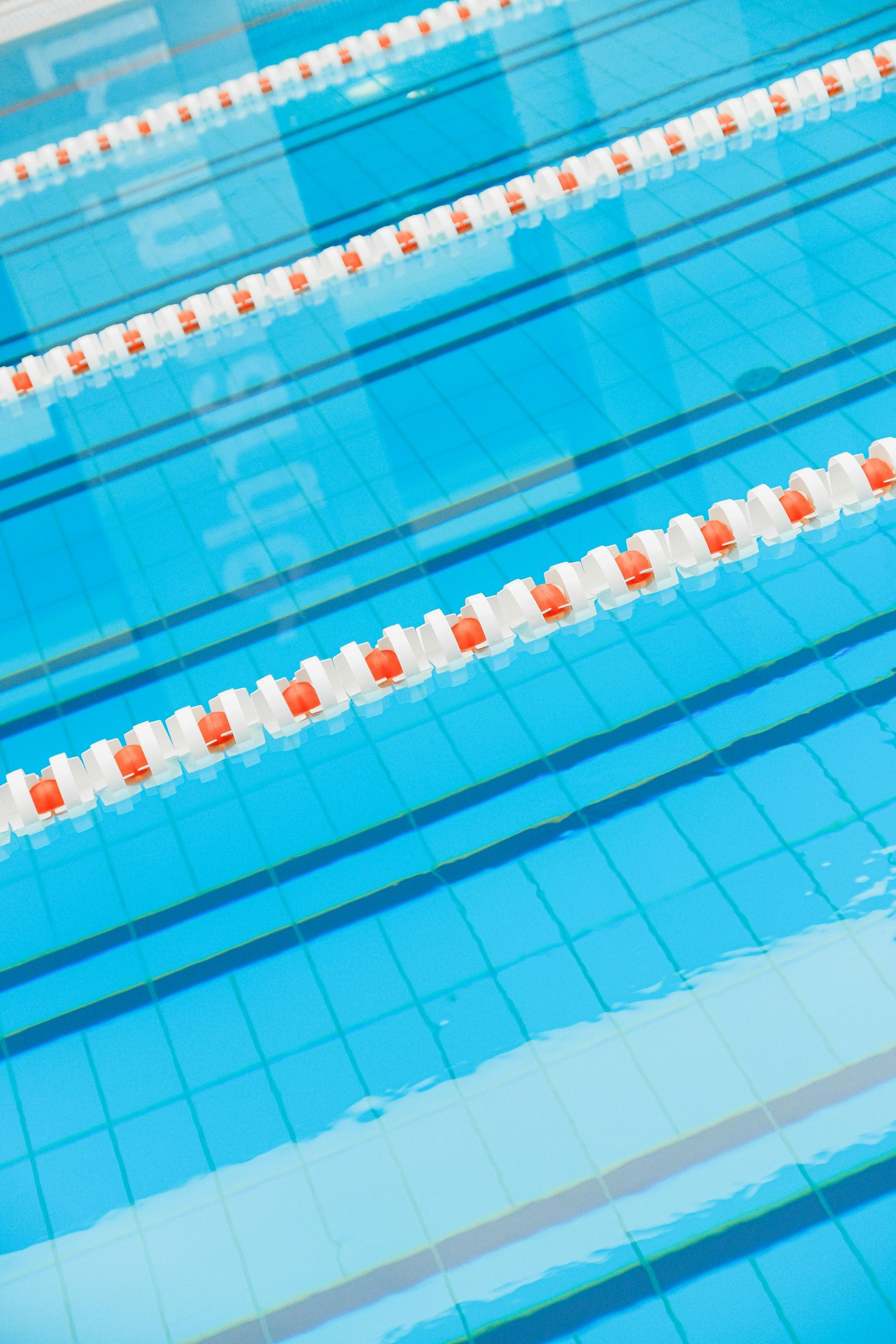 Blue swimming pool with lane markers and orange buoys.