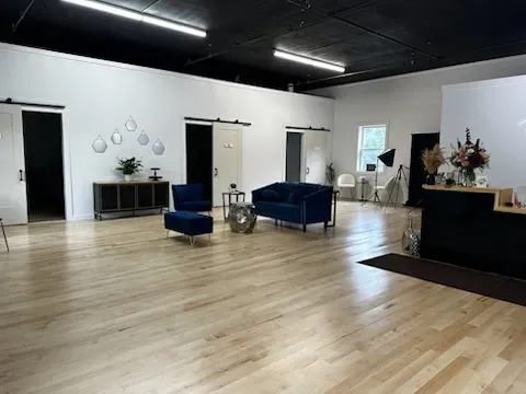A large room with hardwood floors and a couch and chairs.