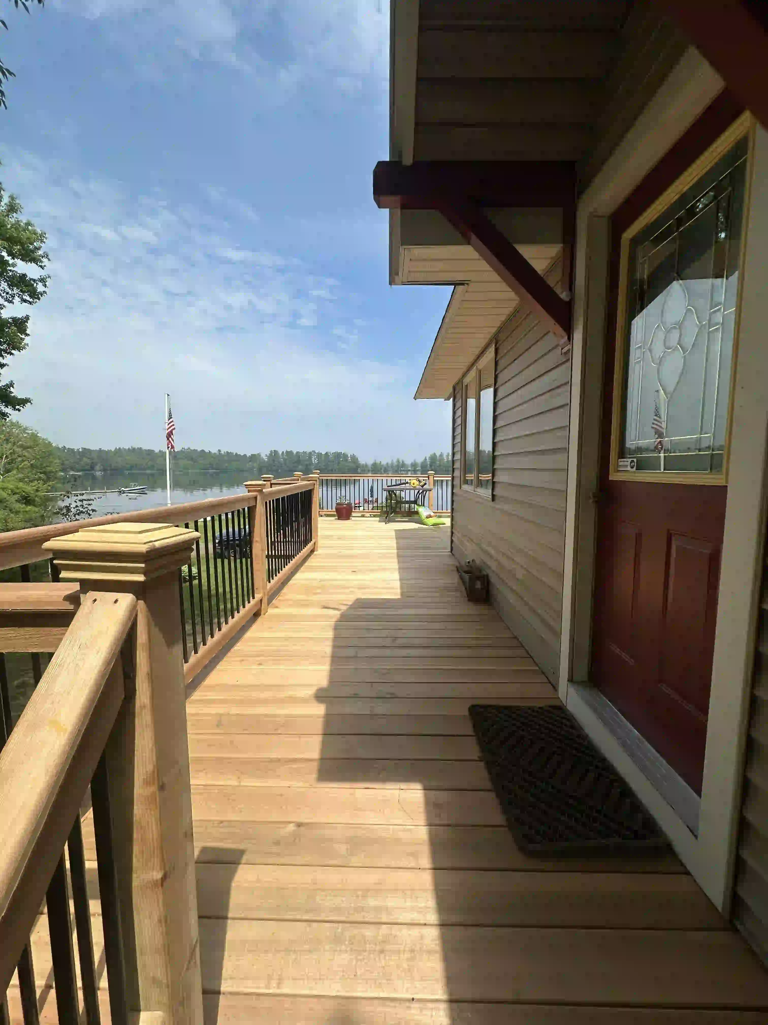 A wooden deck leading to a house with a view of a lake.