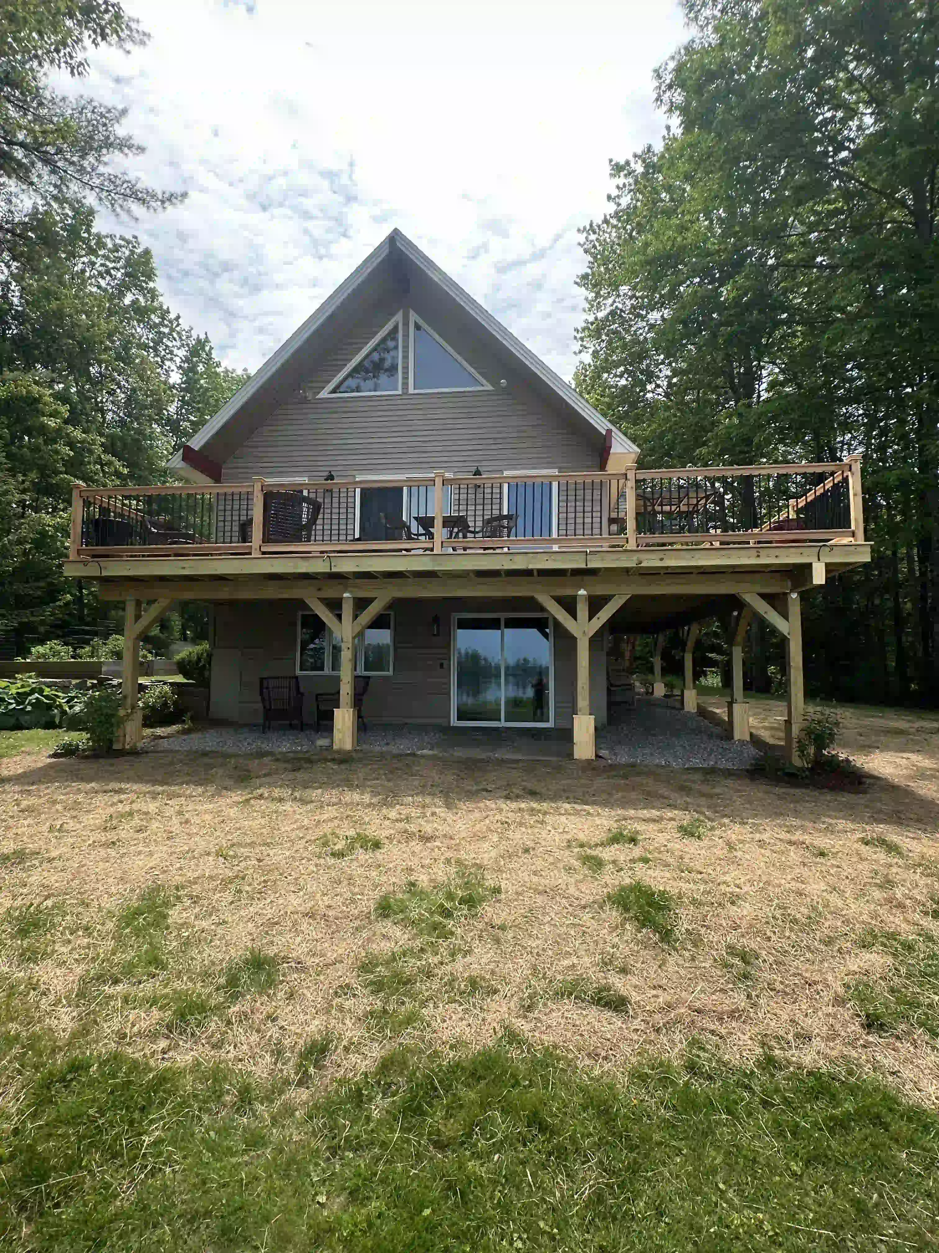 A large house with a large deck in the middle of a field.