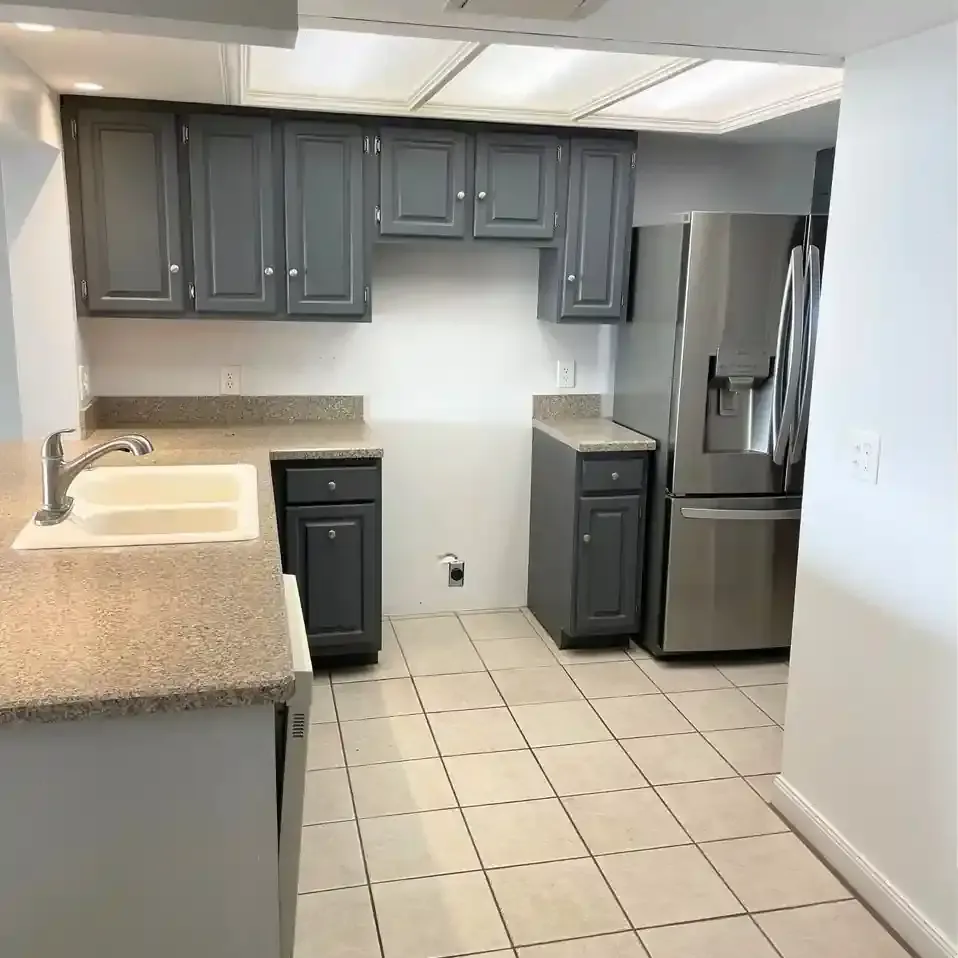 Gray kitchen cabinets and appliances; beige countertops and floor.