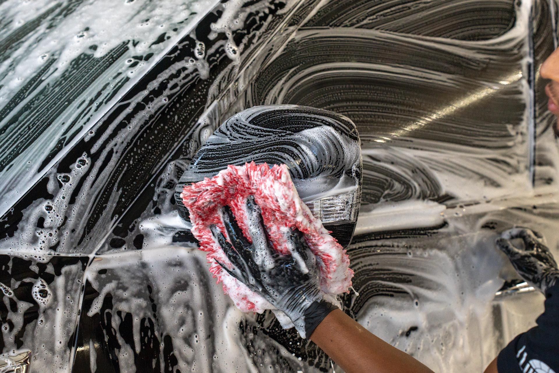 Hand peeling protective film from a glossy black car dashboard trim panel
