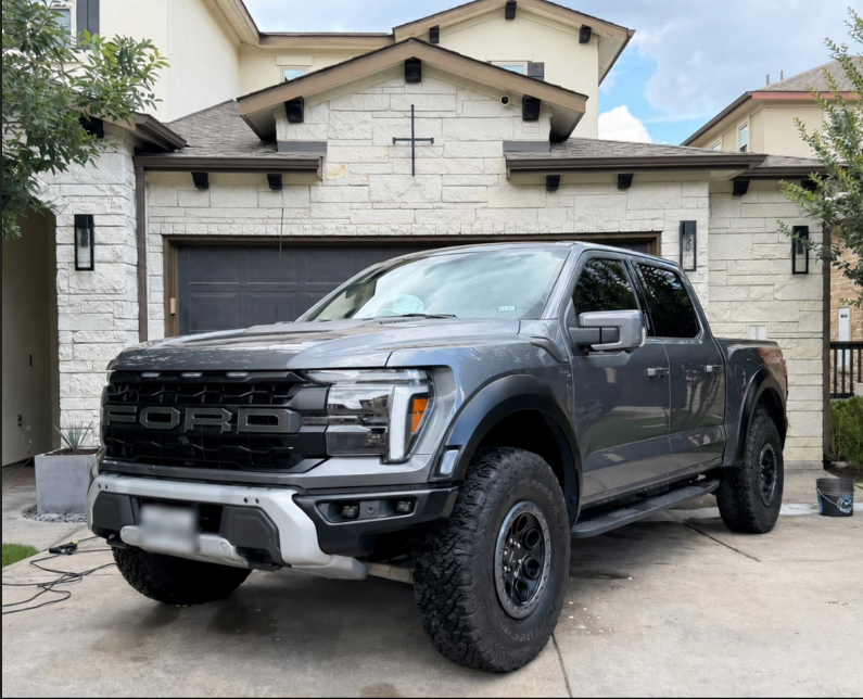 Gray Ford pickup truck parked in a driveway in front of a stone house