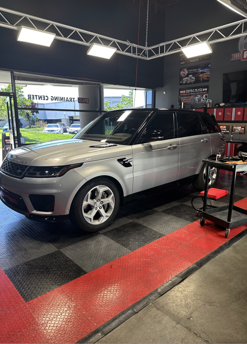 Silver SUV inside an auto detailing shop with black-and-red floor tiles and bright overhead lights