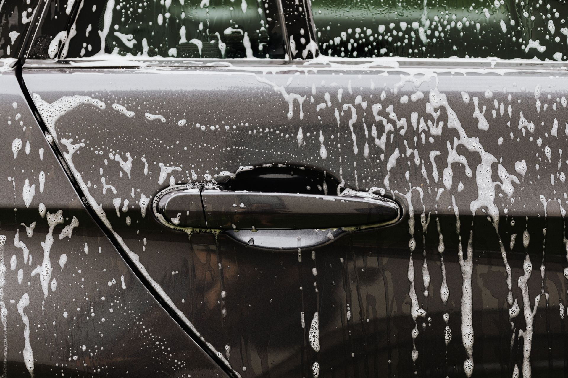 Technician polishing a car windshield with a cloth and spray bottle