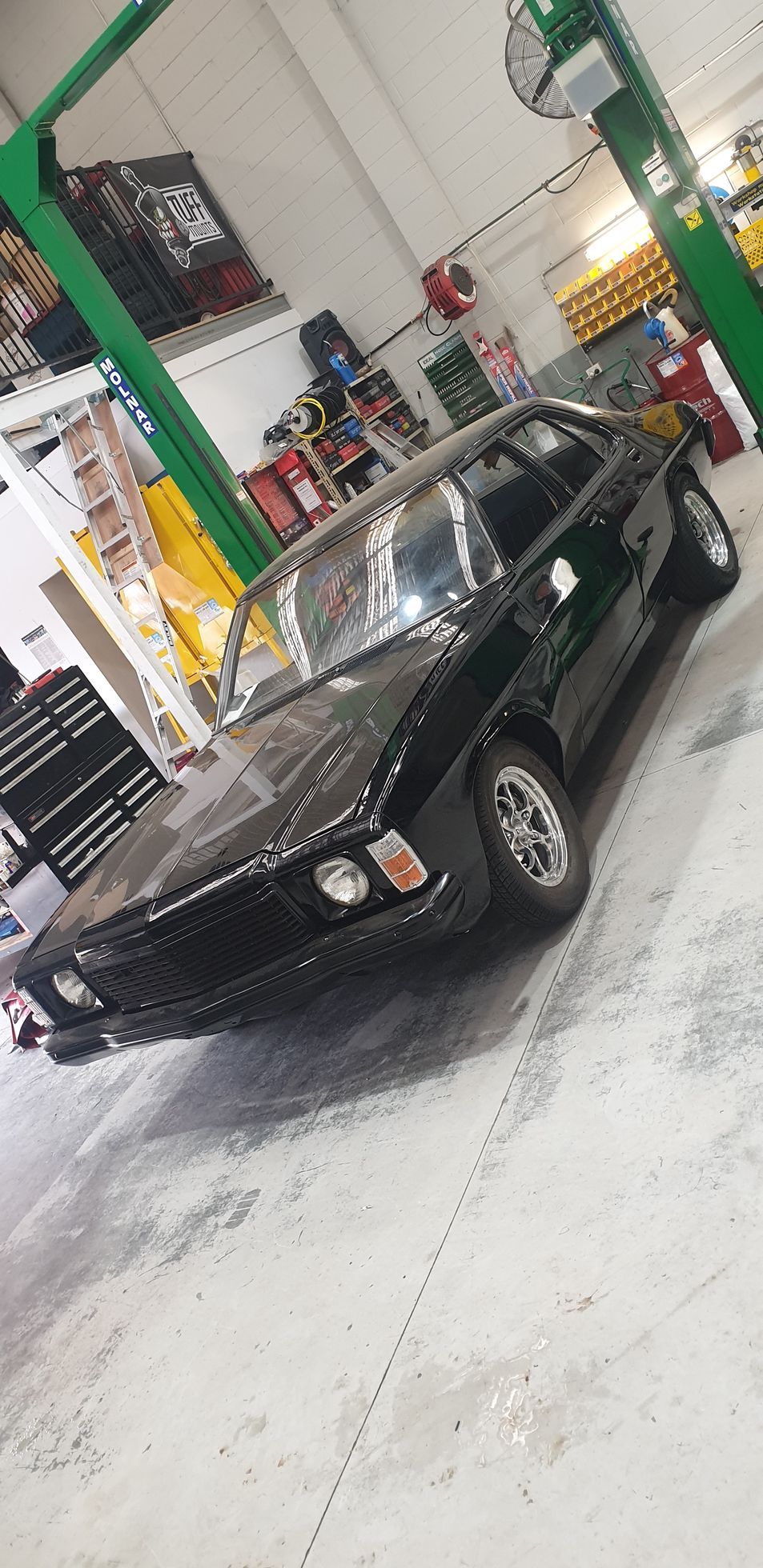 Black classic car in a workshop, parked near a green lift  — Cartech Australia in Albury, NSW