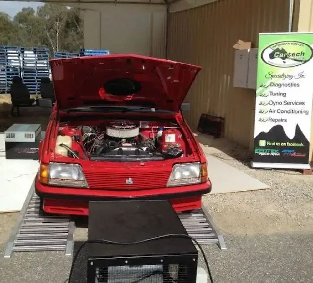 Red Car With Hood Open on Dynamometer