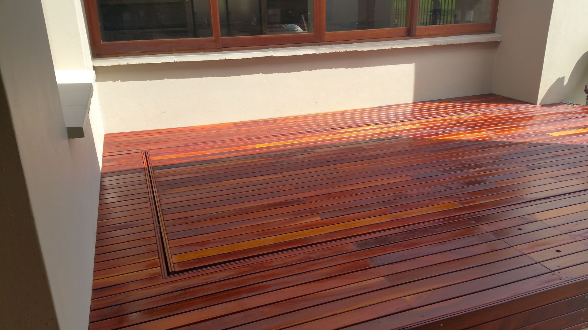 A wooden deck with a window in the background.