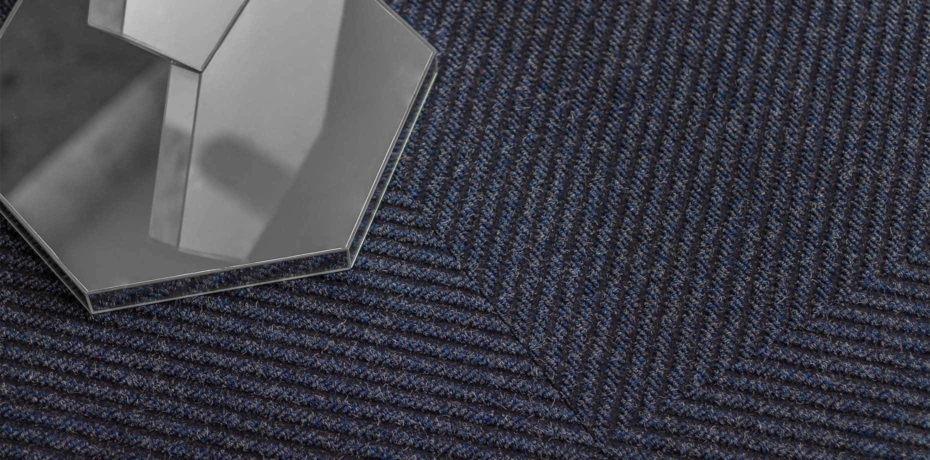 A cube is sitting on top of a blue carpet.