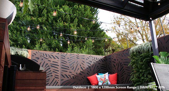 A patio with a couch , chairs , and a tree in the background.