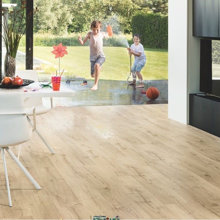 Two children are playing in a room with a wooden floor