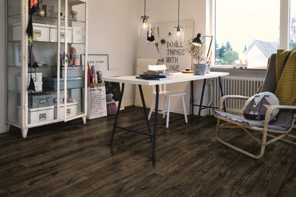 A living room with a wooden floor , a desk , a chair and a glass cabinet.