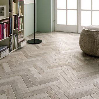 A living room with a herringbone floor and a bookshelf.