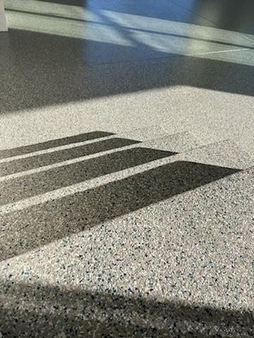 Shadows of steps on a terrazzo floor. Sunlight casts long shadows.