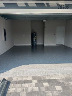 Empty garage with a gray epoxy floor, water heater, and a door.