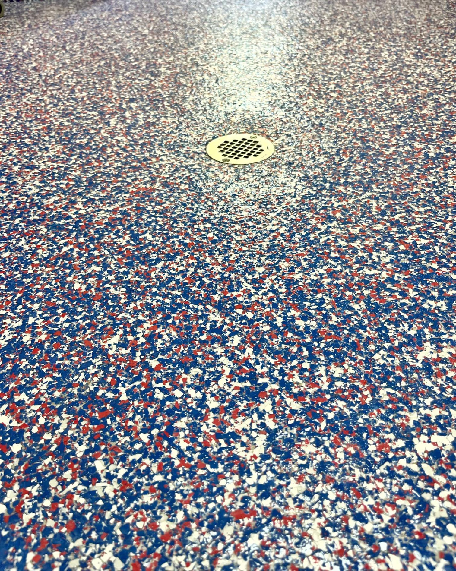 Blue, white, and red speckled epoxy floor with a circular drain.