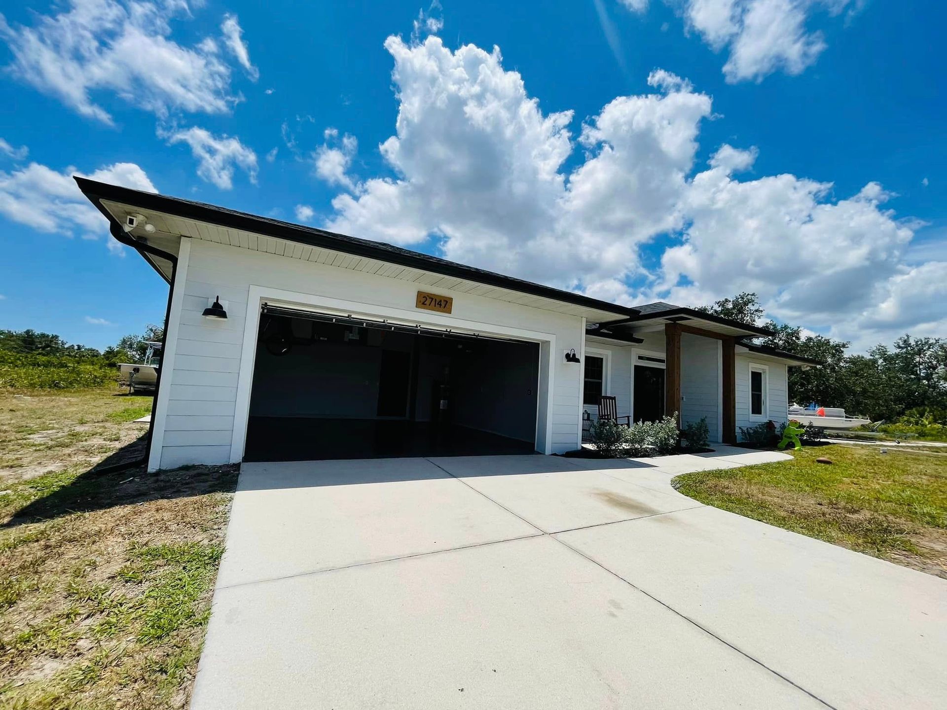 White modern house with an open garage, driveway, and blue sky.
