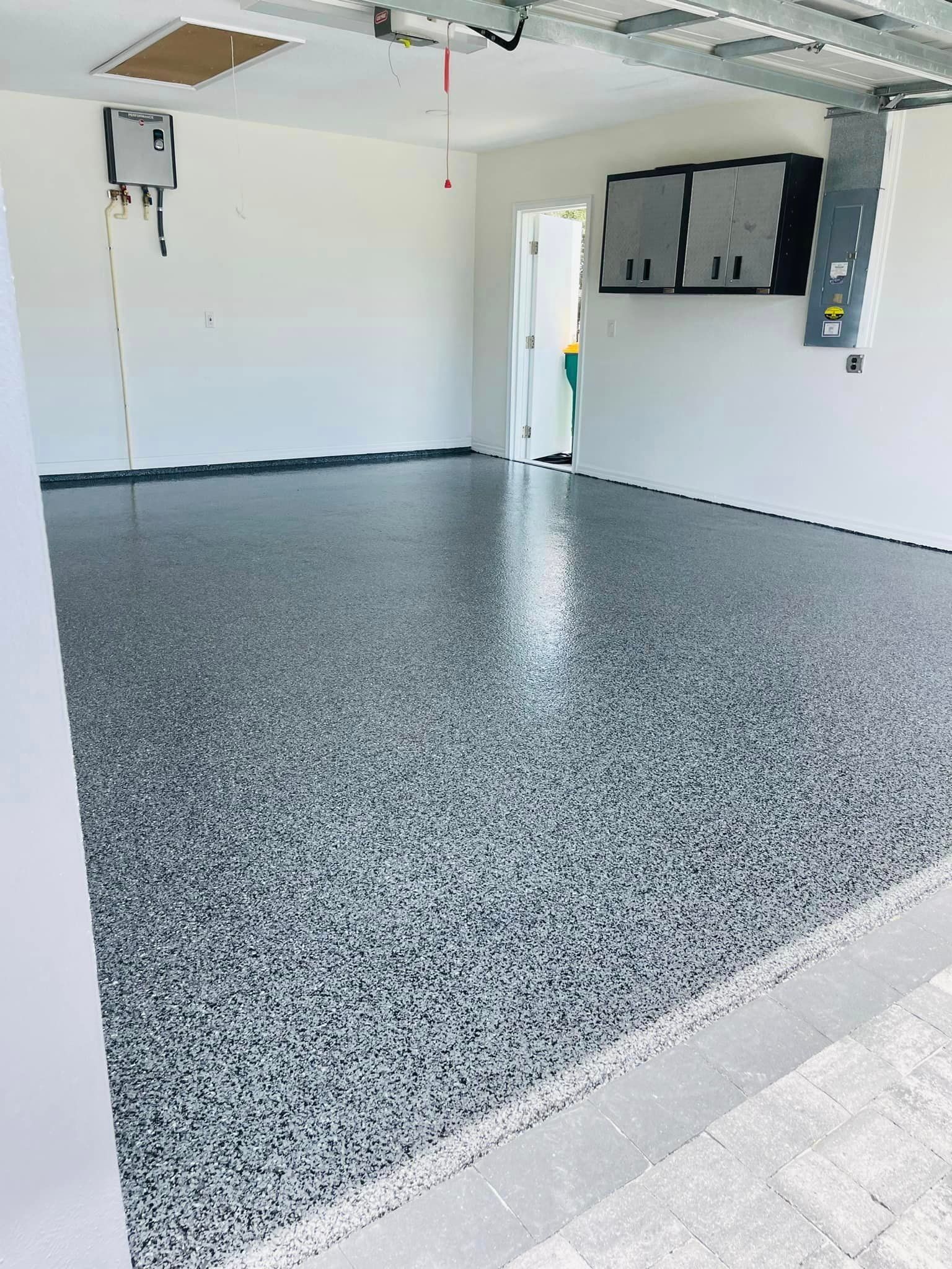 Garage with a speckled gray epoxy floor, white walls, and electrical components.