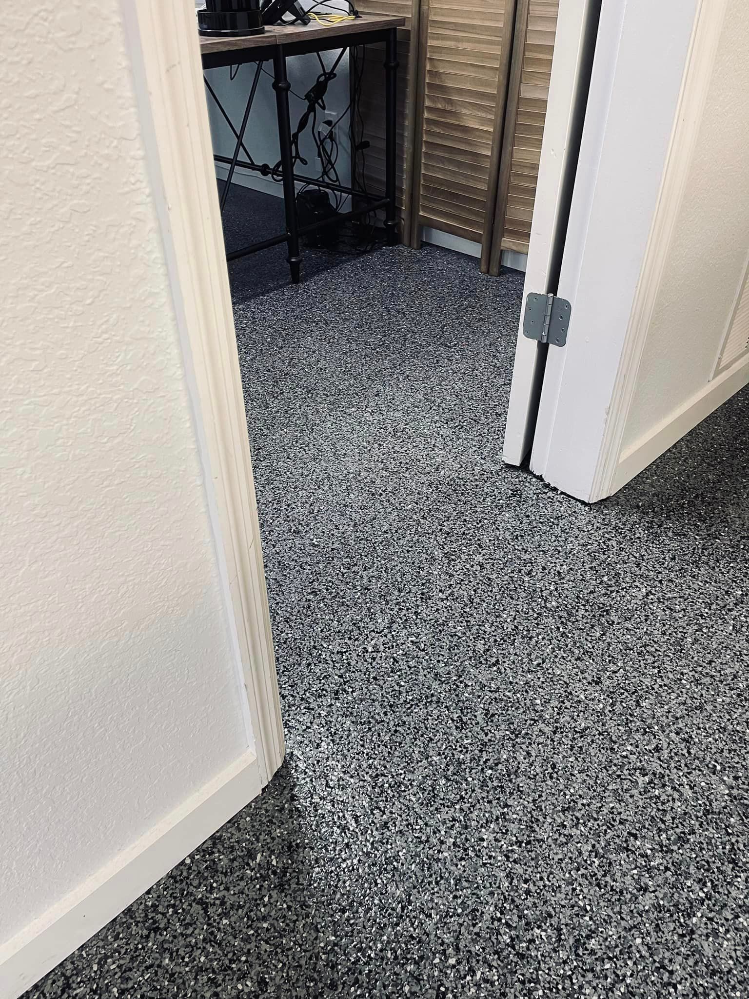 Doorway with speckled floor; white walls, office with desk visible through opening.