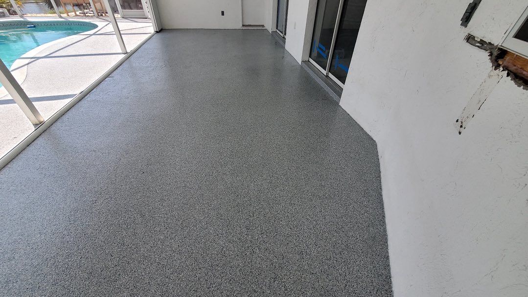 Grey speckled epoxy-coated patio floor next to a white wall and a pool.